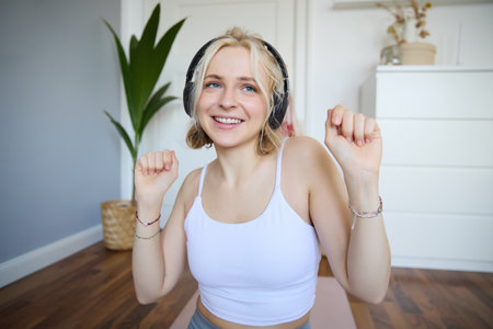 Close up of athletic young woman, cute female model in wireless headphones, dancing to favorite song, listens to music in earphonesの写真素材
