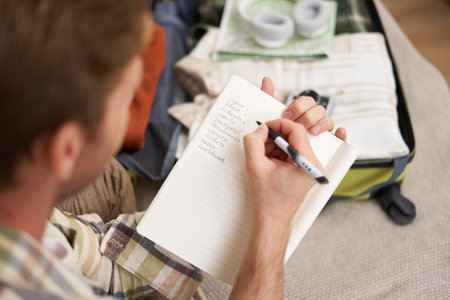 Close up portrait of man going through check-list, packing for holiday, looking at items he wants to bring on vacationの写真素材