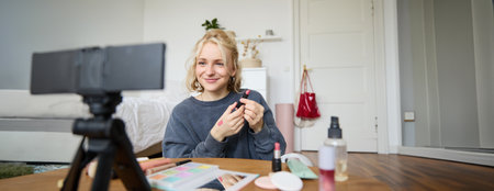Portrait of young content maker, woman blogger recording a video on digital camera, showing lipstick colour to her followers, creating lifestyle vlog for social media accountの写真素材