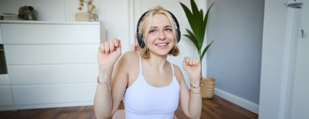 Close up of athletic young woman, cute female model in wireless headphones, dancing to favorite song, listens to music in earphonesの写真素材