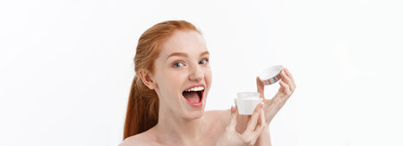 portrait of beautiful woman smiling while taking some facial cream isolated on white background with copy space.の写真素材