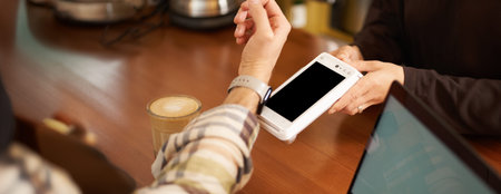 Man in cafe paying contactless using his digital watch on wrist, holding it close to the POS...