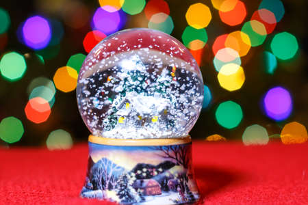 Christmas Snow Globe in front of Christmas tree lights closeup, blurred backgroundの写真素材