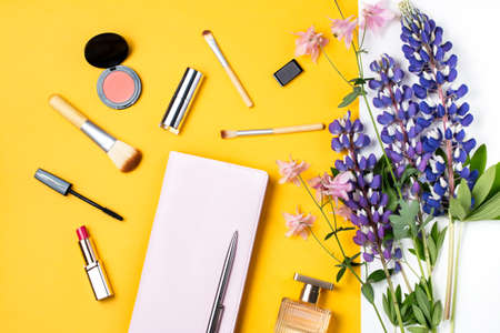 Feminine desk workspace with diary, makeup products, flowers, perfumeの写真素材