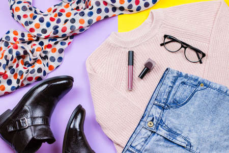 Autumn female clothing - pink sweater, blue jeans, leather handbag, printed scarf, accessories and make up productsの写真素材