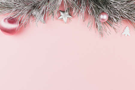 Christmas border with fir branches, christmas balls and silver ornaments on pastel pink backgroundの写真素材