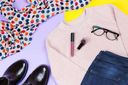 Autumn female clothing - pink sweater, blue jeans, leather handbag, printed scarf, accessories and make up productsの写真素材