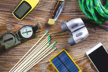 Hiking or travel equipment with boots, compass, binoculars, matches on wooden background. Active lifestyle concept. Top viewの写真素材