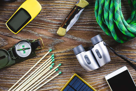 Hiking or travel equipment with boots, compass, binoculars, matches on wooden background. Active lifestyle conceptの写真素材