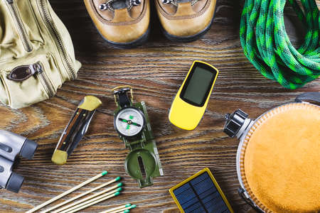Hiking or travel equipment with boots, compass, binoculars, matches on wooden background. Active lifestyle conceptの写真素材