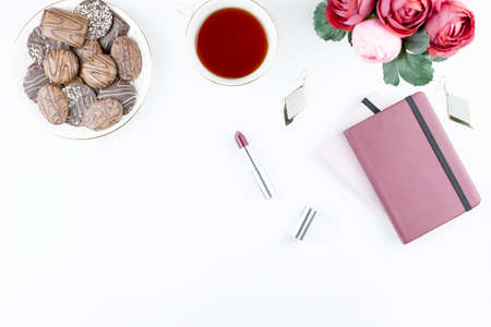 Flat lay home office desk. Feminine workspace with diary, flowers, sweets, fashion accessories. Fashion blogger concept.の写真素材