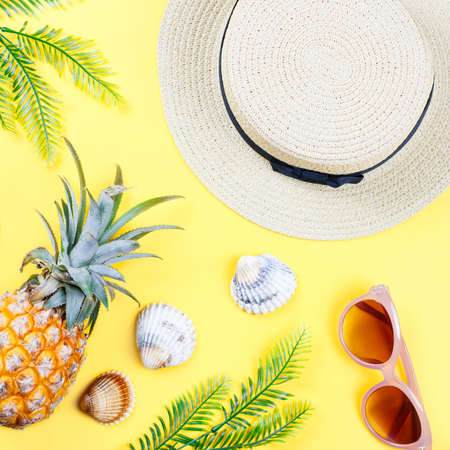 Tropical summer concept with woman fashion accessories, leaves and pineapple on yellow background. Flat lay, top viewの写真素材
