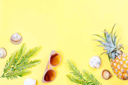 Tropical summer concept with woman fashion accessories, leaves and pineapple on yellow background. Flat lay, top viewの写真素材