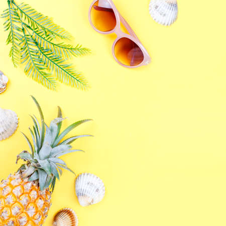 Tropical summer concept with woman fashion accessories, leaves and pineapple on yellow background. Flat lay, top viewの写真素材