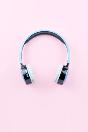 Blue wireless headphones close up on pastel pink background. Flat lay, top viewの写真素材