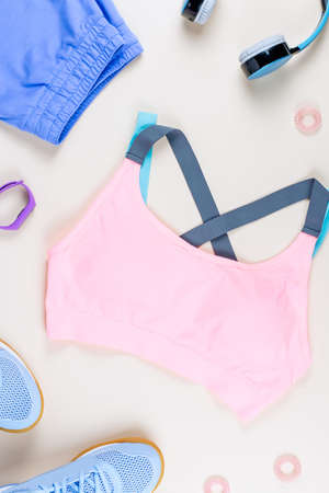 Woman sport clothes, sneakers, headphones and fitness tracker on neutral background. Sport fashion concept. Flat layの写真素材