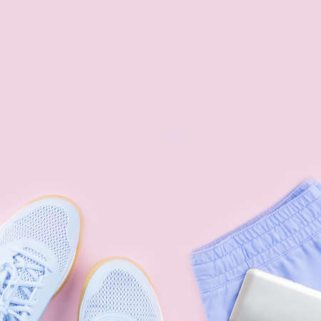 Violet female sneakers, running shorts and smartphone on pink background. Flat lay, copy space.の写真素材