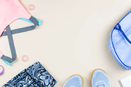 Woman sport clothes, sneakers, headphones and fitness tracker on neutral background. Sport fashion concept. Flat lay, top viewの写真素材