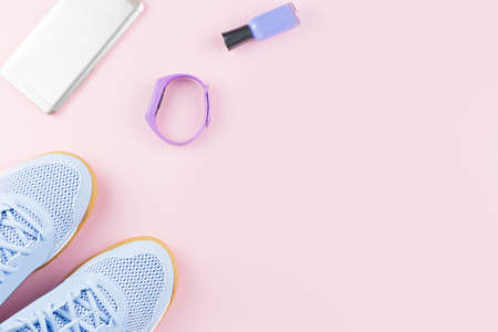 Woman sneakers, fitness tracker and smartphone on pastel pink background. Sport fashion concept. Flat lay, top viewの写真素材