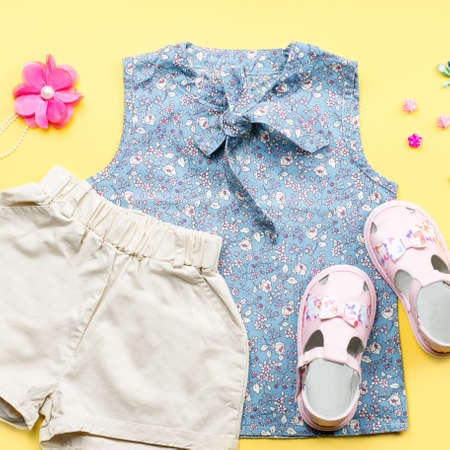 Little girl clothes collection flat lay with blue top, shorts, sandals on pastel background.の写真素材