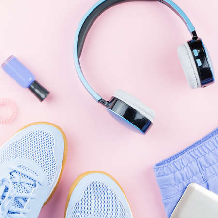 Woman sneakers, headphones, fitness tracker and running clothes on pastel background. Sport fashion concept. Flat layの写真素材