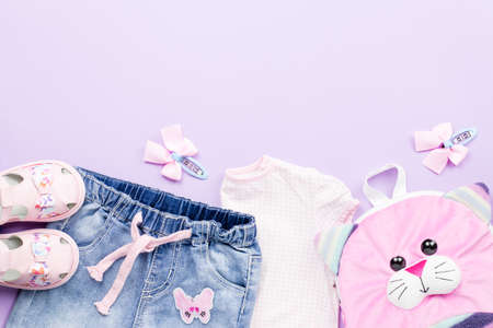 Little girl clothes collection flat lay with t-shirt, jeans, sandals, backpack on pastel background.の写真素材