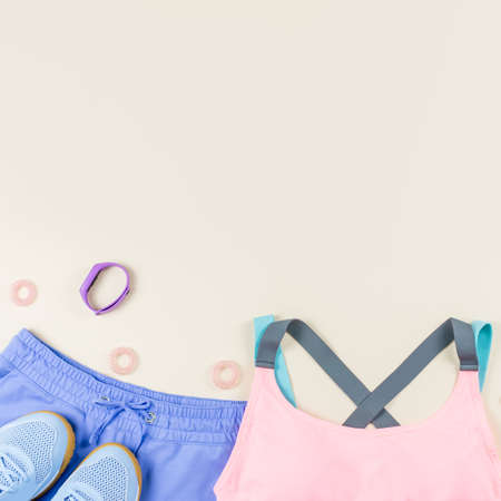 Woman sport clothes, sneakers, headphones and fitness tracker on neutral background. Sport fashion concept. Flat layの写真素材