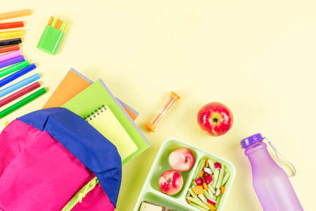 School concept flat lay. Kid backpack, lunchbox, water bottle, notebook, markers on wooden desktopの写真素材