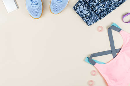 Woman sport bra, leggins, sneakers, headphones and fitness tracker on neutral background. Sport fashion concept.の写真素材