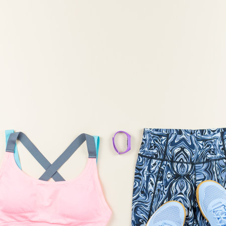 Woman sport bra, leggins, sneakers, headphones and fitness tracker on neutral background. Sport...