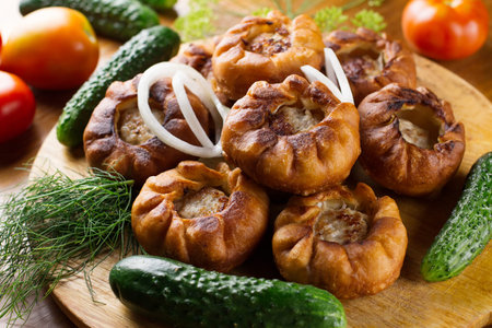 Fried meat pies belyash with vegetables on wooden boardの写真素材