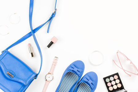 Fashion blogger workspace flat lay with navy flats, cosmetics, purse, sunglasses. Top view