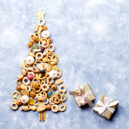 Christmas tree made of cookies and presents on blue background.