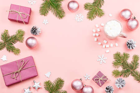 Christmas background with fir tree branches, red giftboxes, decorations, hot drink with marshmallows on pink. Copy spaceの写真素材