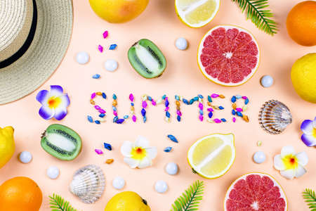 Colorful summer concept flat lay with fresh juice, tropical fruits, lollipops and multicolor seashellsの写真素材