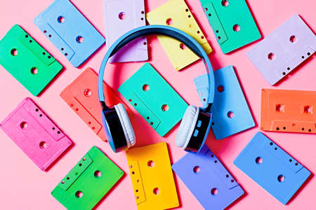Painted audio cassettes and blue headphones on pink background, copy space, top view. Retro musical backgroundの写真素材