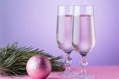 Christmas card with two glasses of champagne, christmas ornaments, fir tree branch in pink colors.の写真素材