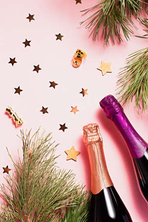 Christmas frame with fir tree, shadows, champagne bottles, glasses, carnival mask, christmas ornaments in pink and purple colors. Copy spaceの写真素材