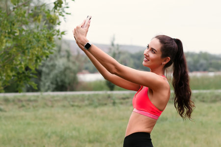 Young attractive toned brunette woman working out outside in a park in crop top and leggins. Healthy...
