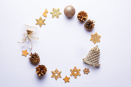 Christmas round frame with golden ornaments, painted snowflakes, pine cones, confetti on grey...
