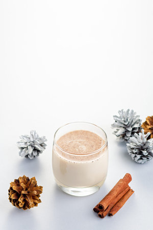 Traditional Christmas cocktail Eggnog with eggs, alcohol, grated nutmeg and cinnamon closeup. Sweet...