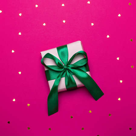 Woman manicured hands holding red and golden wrapped present or giftbox on deep red background, copy space, top view. Flat lay, giving presents concept. Background for Valentine's Day, Mother's Day.の写真素材