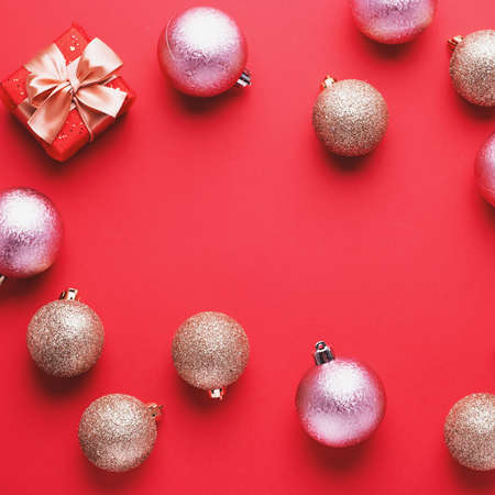 Golden Christmas baubles and red gift boxes on red background in chaotic order, copy space. Minimal flat lay with wrapped presents and ornamentsの写真素材