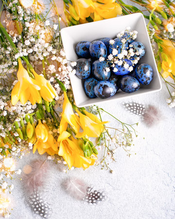 Easter creative card with quail eggs painted blue, feathers and gypsophila flowers flat lay, pastel...