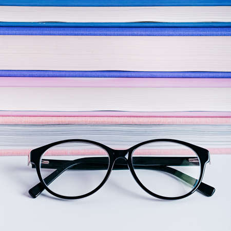 Closeup of reading glasses against stack of books, book reading conceptの写真素材