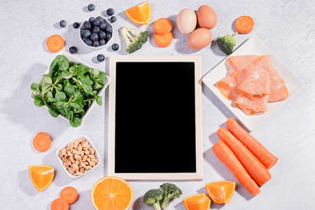 Foods that help maintain eyes healthy, products for keeping good vision. Black board with copy space, assortment of food for eye health on concrete background, flat lay, top view, nobodyの写真素材