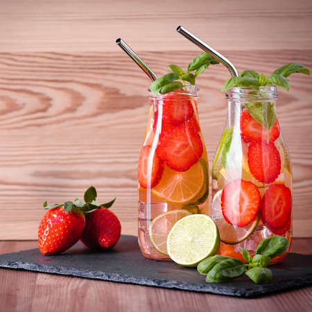 Refreshing drink or water with citrus fruits lemon and lime and basil in mason jar with reusable metal straws. Healthy lemonade drink in glass jar on kitchen table, zero waste, sustainable lifestyleの写真素材