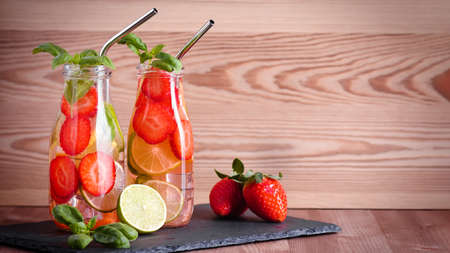 Refreshing drink or water with citrus fruits lemon and lime and basil in mason jar with reusable metal straws. Healthy lemonade drink in glass jar on kitchen table, zero waste, sustainable lifestyleの写真素材