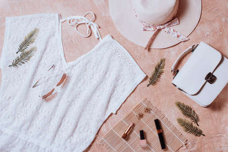 Fashion female clothes and accessories for beach destinations or summer vacation. Flat lay with woman white clothing and purse, make up items on terracota background, woman travel fashion conceptの写真素材