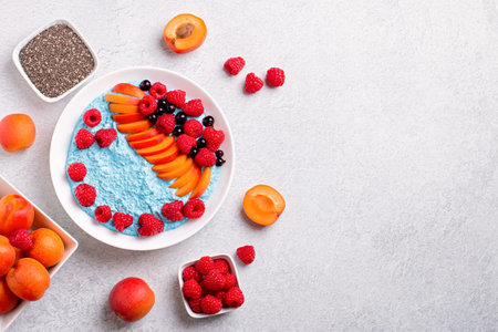 Chia seeds pudding bowl with apricot, raspberry on concrete background. Blue mousse with chia seeds,...